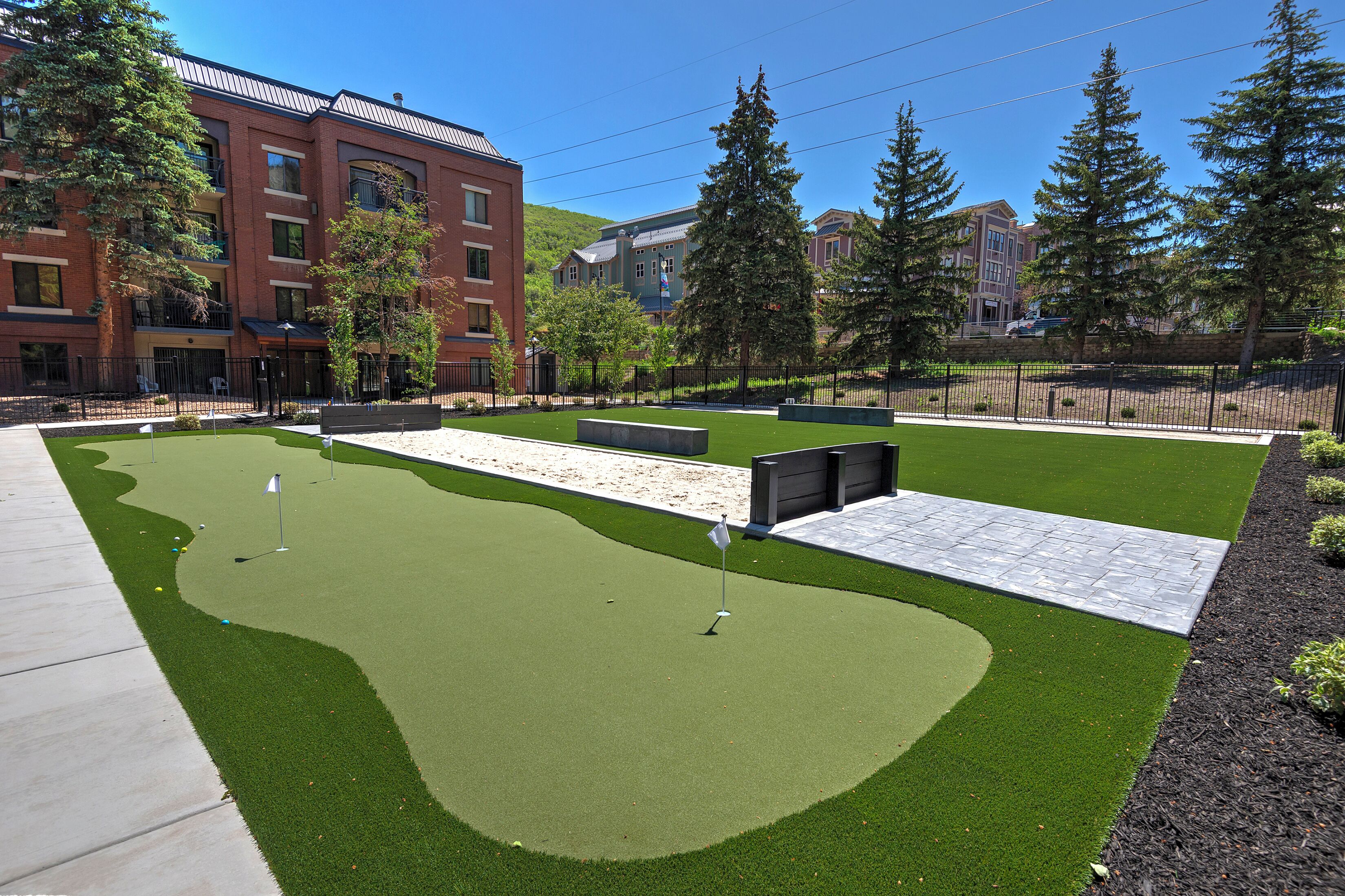 Un campo de golf con putting green, búnkeres de arena y un mástil con bandera.