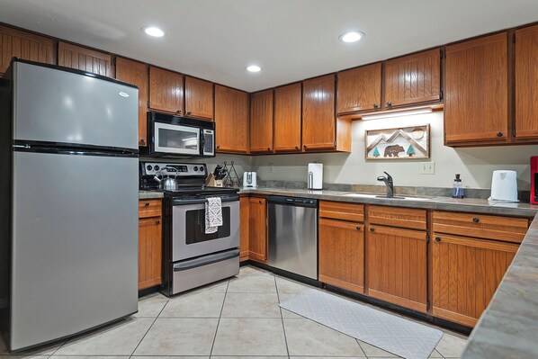 A kitchen with wooden cabinets, stainless steel appliances, and a tiled floor. - Main St/Steps to Town Lift/Hot Tubs Pool/Free Parking (Park City)