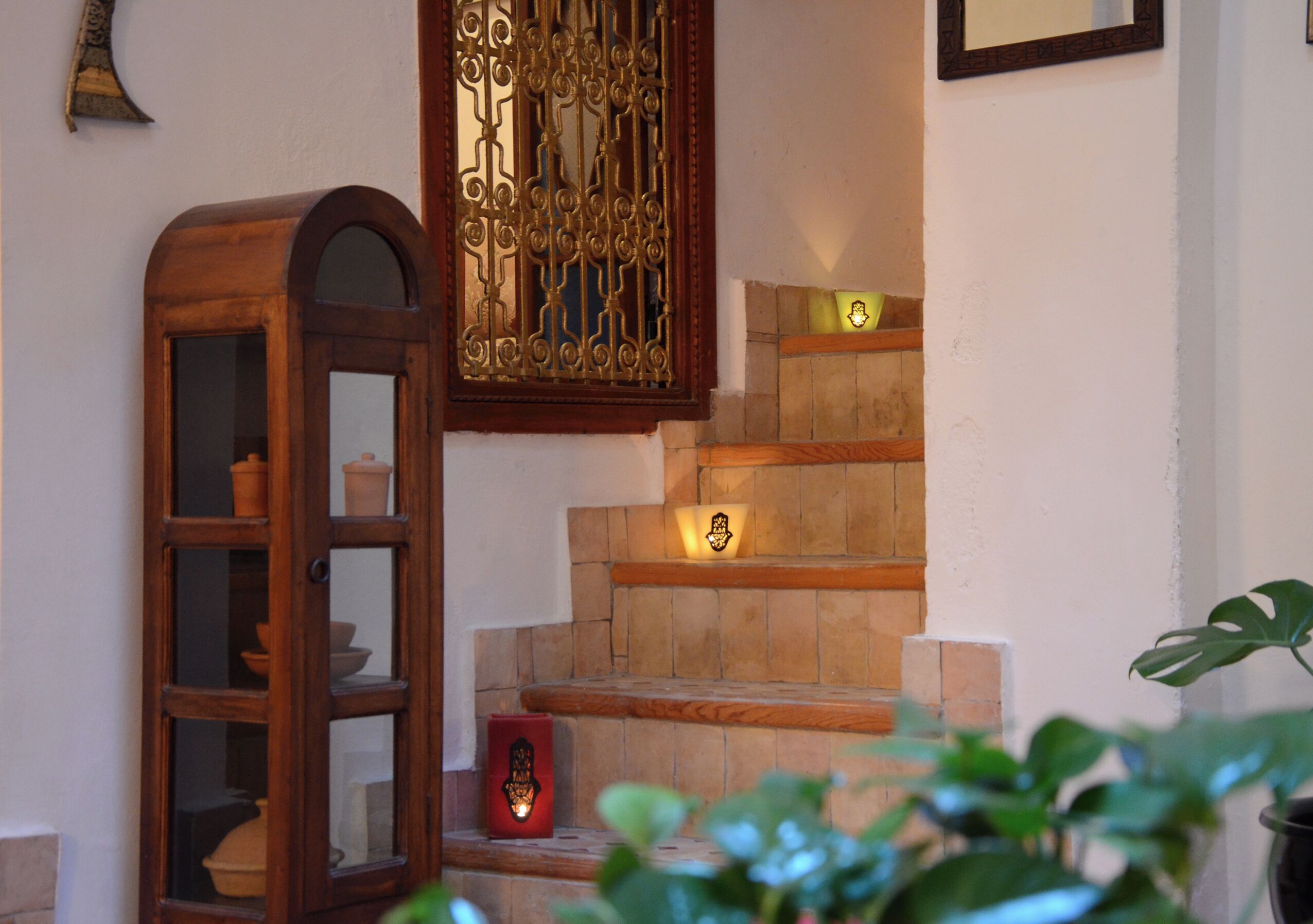 Un escalier avec une rampe en bois, un meuble en bois doté de portes en verre et un objet décoratif fixé au mur.