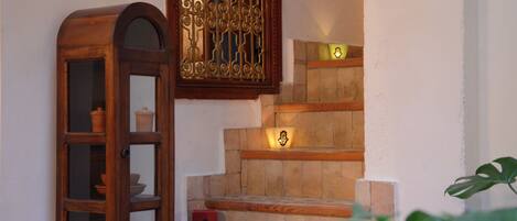 Un escalier avec une rampe en bois, un meuble en bois doté de portes en verre et un objet décoratif fixé au mur.