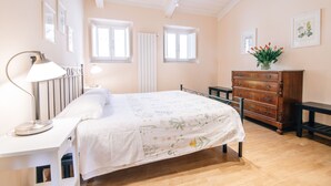 Un dormitorio con cama, mesita de noche, lámpara, cómoda y obras de arte en las paredes.