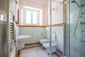 A bathroom with a glass-enclosed shower, a sink, and a toilet.