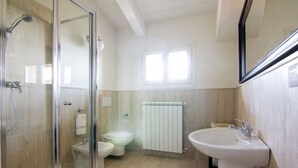 Un baño moderno con cabina de ducha de vidrio, inodoro, lavabo y radiador.