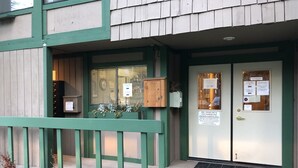 L'ingresso di un edificio con una porta verde, una cassetta postale e un avviso con annunci.