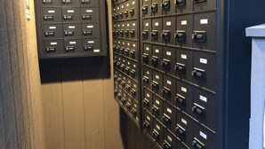 Una fila di armadietti metallici con etichette numerate, una panca di legno e una bacheca informativa a muro.