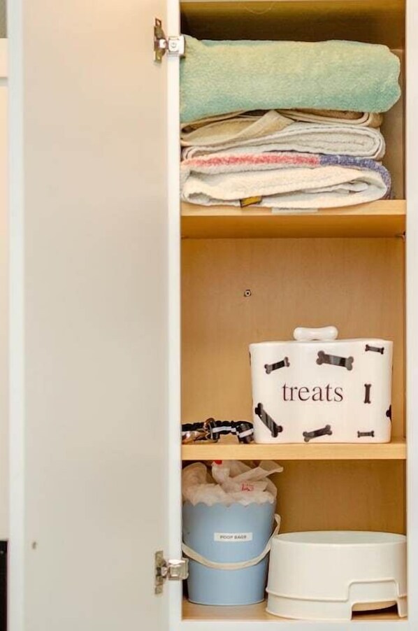 Un placard contenant des serviettes pliées, un récipient pour les friandises et un récipient pour les sacs à excréments.