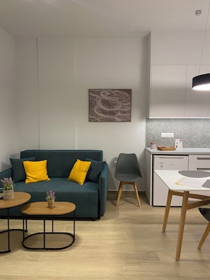 A modern living room with a teal sofa, a small round table, and a gray chair.