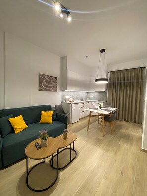 A modern living room with a sofa, coffee table, and a dining area with a table and chairs. - Economic Studio B1 (Iraklion Crete)