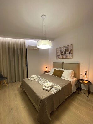 A hotel room with a bed, bedside tables, a chair, a painting, and a curtain. - Economic Studio B1 (Iraklion Crete)