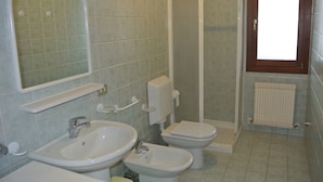 A bathroom with two sinks, a toilet, a shower, and a mirror.