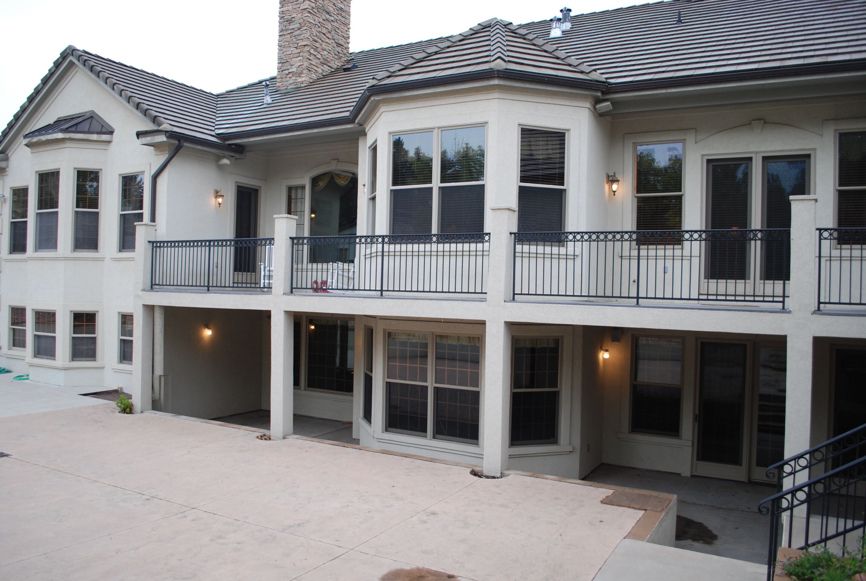 A two-story house with a balcony, large windows, and a chimney.