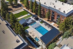 An aerial view of a residential area with a swimming pool, outdoor seating, and a building with a flat roof.