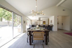 Enjoy meals in this dining area with a large table for four, a chandelier, and a view of the outdoors.