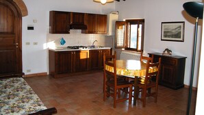 Une cuisine avec des meubles de rangement en bois, une cuisinière et une table à manger avec des chaises.