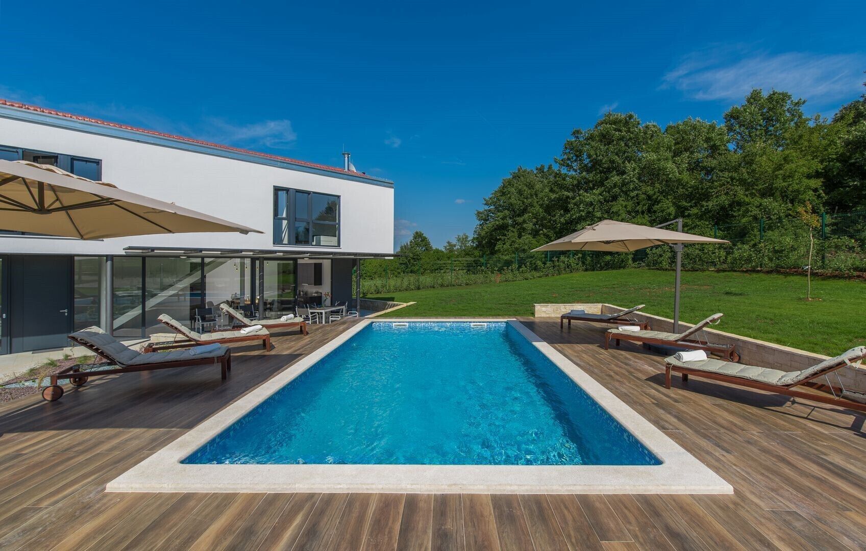 Una casa moderna con piscina, terrazza in legno e mobili da esterno.