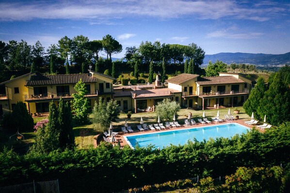 Relax in a pool surrounded by lush greenery and mature trees, with expansive views of the countryside from multiple levels and balconies.
