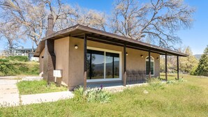 A modern house with a large glass window, a brick chimney, and a covered porch. - NEWLY RENOVATED 2bedroom in heart of Oakhurst (Oakhurst)