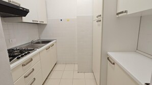 A compact kitchen with white cabinets, a gas stove, and a sink.
