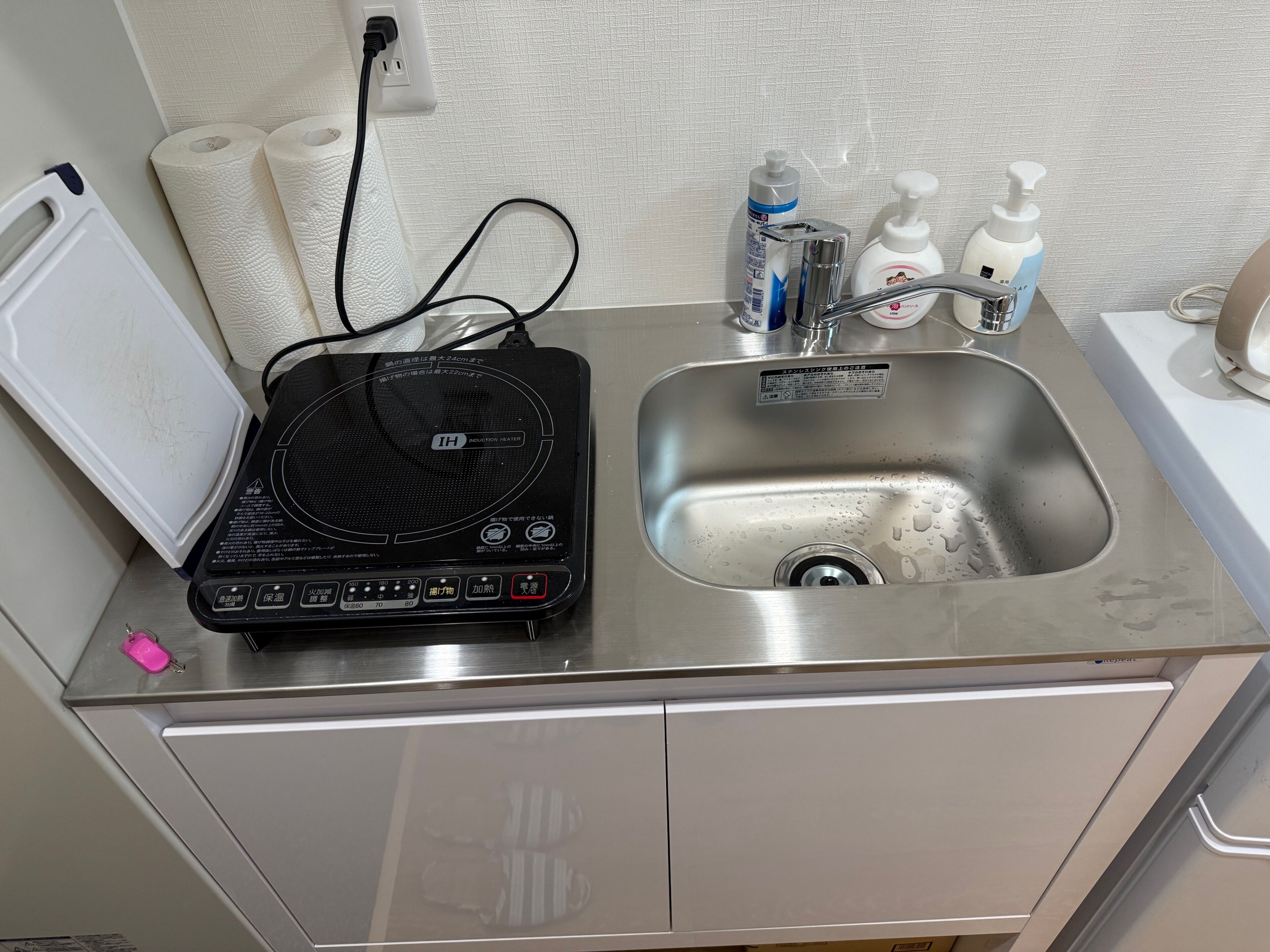 Une salle de bain équipée d’un lavabo, de papier toilette, de savon pour les mains et d’un radiateur à induction portatif.