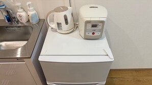 A compact kitchen with a refrigerator, a kettle, and a coffee maker on the countertop. - Near Shibuya! Bright and Clean Olympic Park (Setagaya)