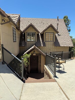 A two-story house with a steeply pitched roof, a front porch with a door marked '1334', and a staircase leading to the entrance.