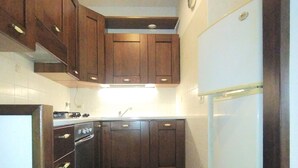 A compact kitchen with dark wooden cabinets, a white refrigerator, and a tiled floor. - EUR Chianesi - IFO (50mt) strategico bilo, ben collegato A/C parcheggio (Rome)