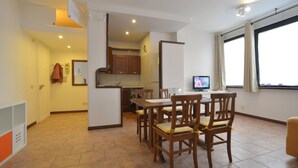 A dining area with a table and chairs, a kitchen in the background, and a TV on a stand. - EUR Chianesi - IFO (50mt) strategico bilo, ben collegato A/C parcheggio (Rome)