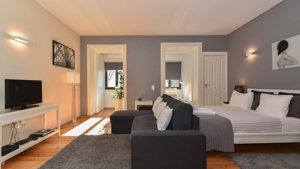 Et moderne soveværelse med seng, sofa, fjernsyn og skrivebord.
