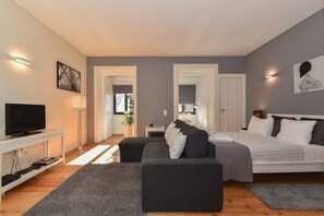 Une chambre moderne avec un lit, un canapé, une télévision et un bureau.