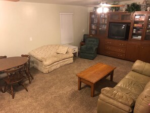 Relax in this inviting living room with a sofa, armchair, coffee table, dining table, and TV.