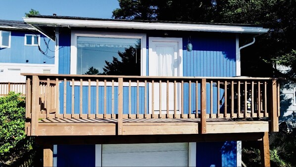 Una casa de dos pisos con terraza de madera y puerta de garaje.