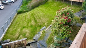 Un barrio residencial con un césped cuidado, un sendero de piedra y una escalera de madera que lleva a una terraza.