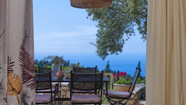 Une terrasse avec une table et des chaises, offrant une vue panoramique sur la mer.