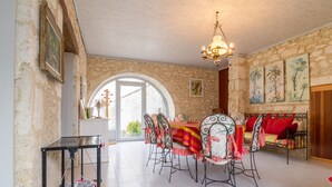 A dining area with a table set for four, a chandelier, and a view through an arched doorway. - Room MAUVE, Bed and Breakfast Saint Roch, indoor heated pool (Tournecoupe)