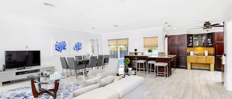 A modern living room with a sofa, TV, and dining area.