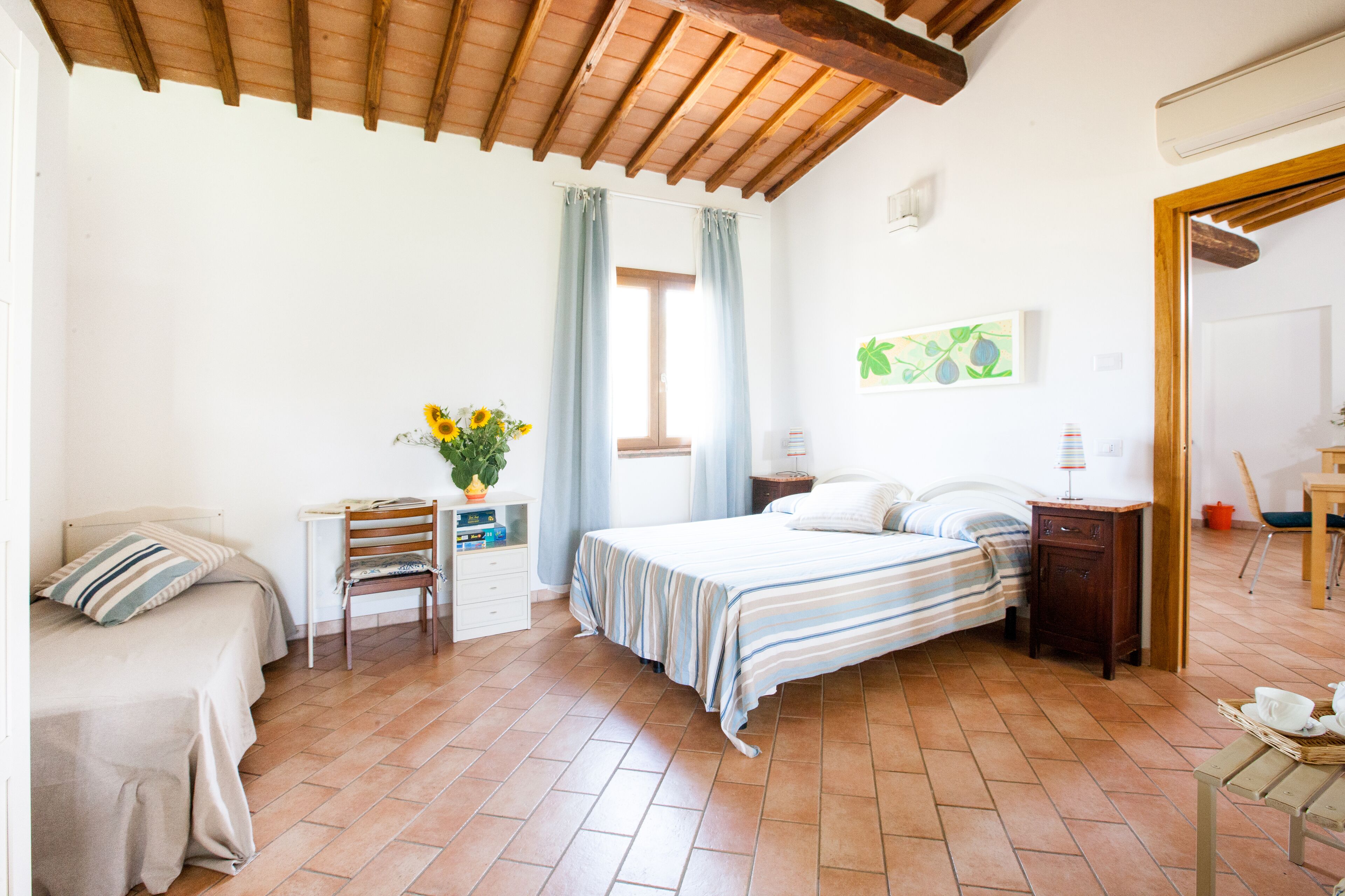 Een slaapkamer met een bed, een stoel, een bureau en een raam met gordijnen.
