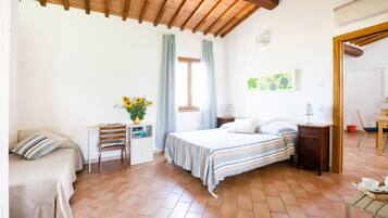 Een slaapkamer met een bed, een stoel, een bureau en een raam met gordijnen.