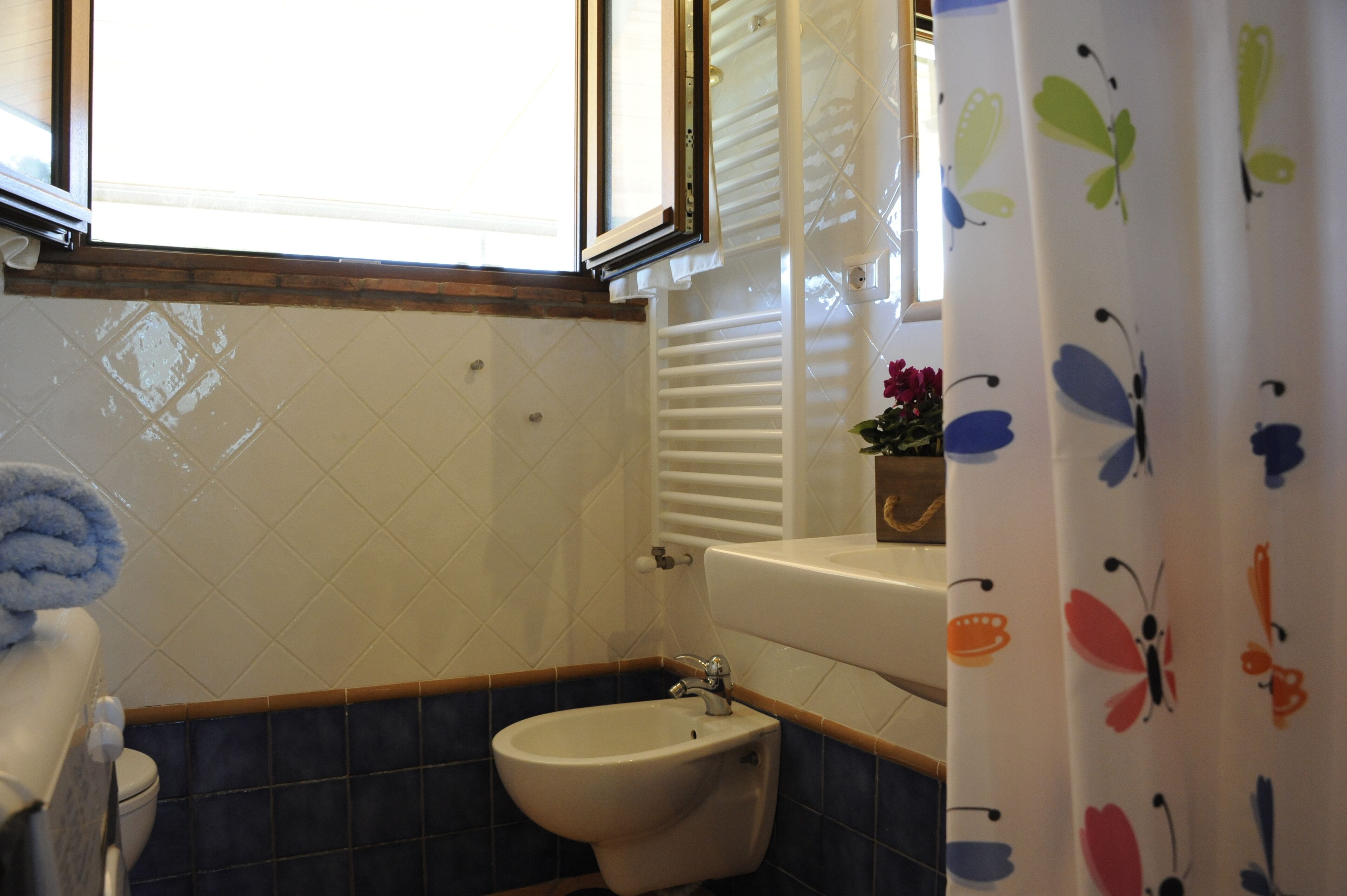 Un baño con bidé, inodoro, lavabo y ventana.