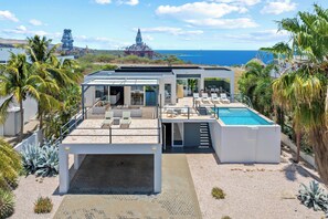 Uma casa moderna com piscina, pátio e vista para o oceano e instalações industriais.