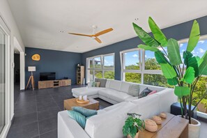 Uma sala de estar moderna com um sofá modular, uma mesa de centro e uma planta grande.