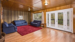 Un vaste espace de vie doté d’un plancher en bois, d’un tapis rouge et de deux canapés bleus.