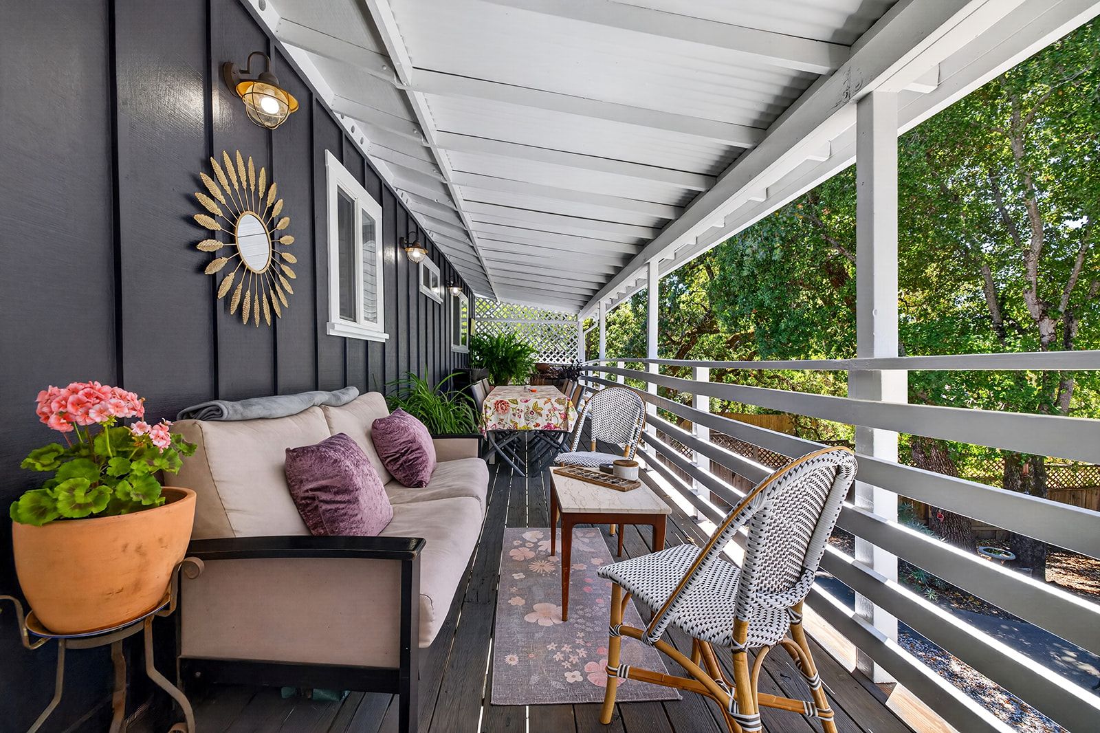 A covered porch with a sofa, chairs, and a table.