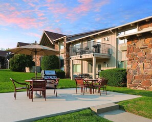 A patio with outdoor furniture, a grill, and a stone building with a balcony. - All the comforts of home! (Afton)