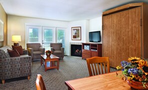 A living room with a sofa, armchairs, a coffee table, a fireplace, a television, and a dining table with flowers. - All the comforts of home! (Afton)
