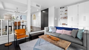 A modern living room with a grey sofa, orange leather chair, and a wooden coffee table.