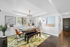 A modern kitchen with a large island, white cabinetry, and a dining area with a bench.
