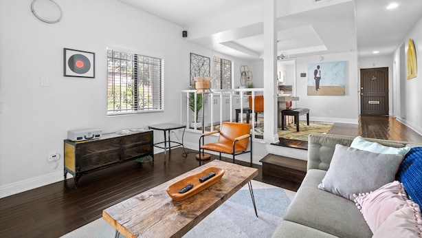 A modern living room with a sofa, a wooden coffee table, a side table, a chair, and a cabinet.
