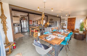 A spacious kitchen with a large island, modern appliances, and a dining area with blue chairs and a wooden table.