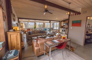 A spacious living area with a large sofa, a dining table, and a kitchen in the background.