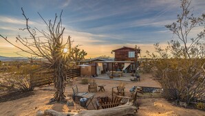 A rustic cabin with a patio, surrounded by desert vegetation. - Diamond Sky Retreat • Joshua Tree, California (Joshua Tree)